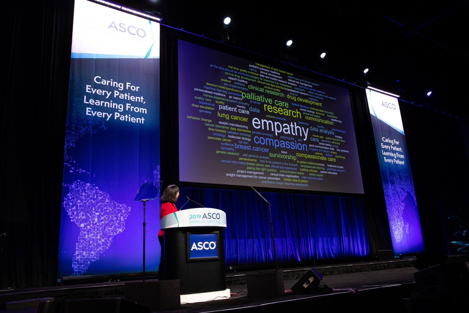 Dr. Bertagnolli in front of a word cloud; the words compassion and empathy are the largest