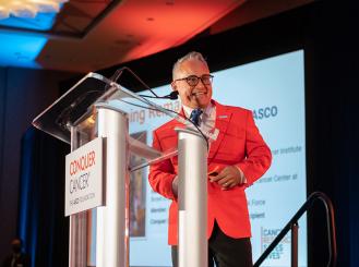 Dr. Don S. Dizon in an orange blazer at a 2022 Conquer Cancer evening event.