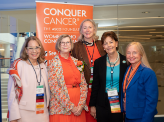 A group photo of ASCO leaders in front of a Conquer Cancer banner.
