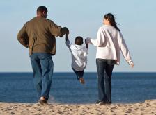Stock image of mother and father holding child on a beach